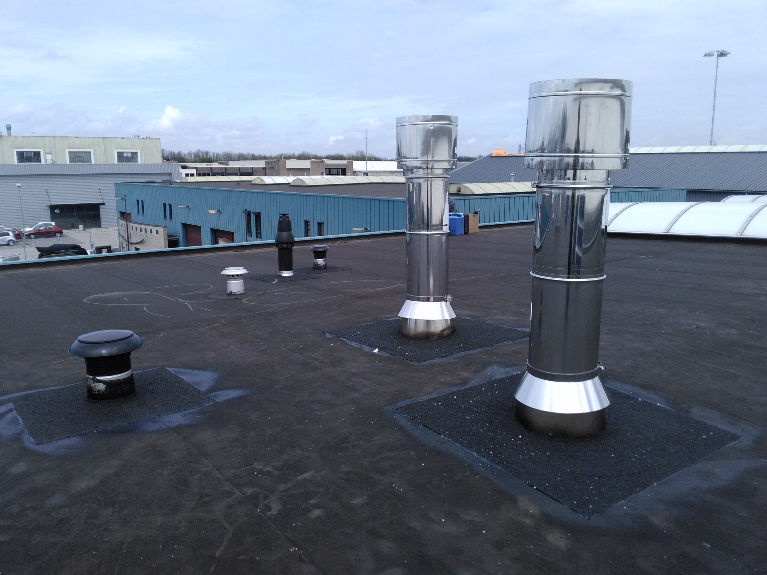 RVS ventilatie- en rookgasafvoeren op een plat dak — installatiewerk op locatie